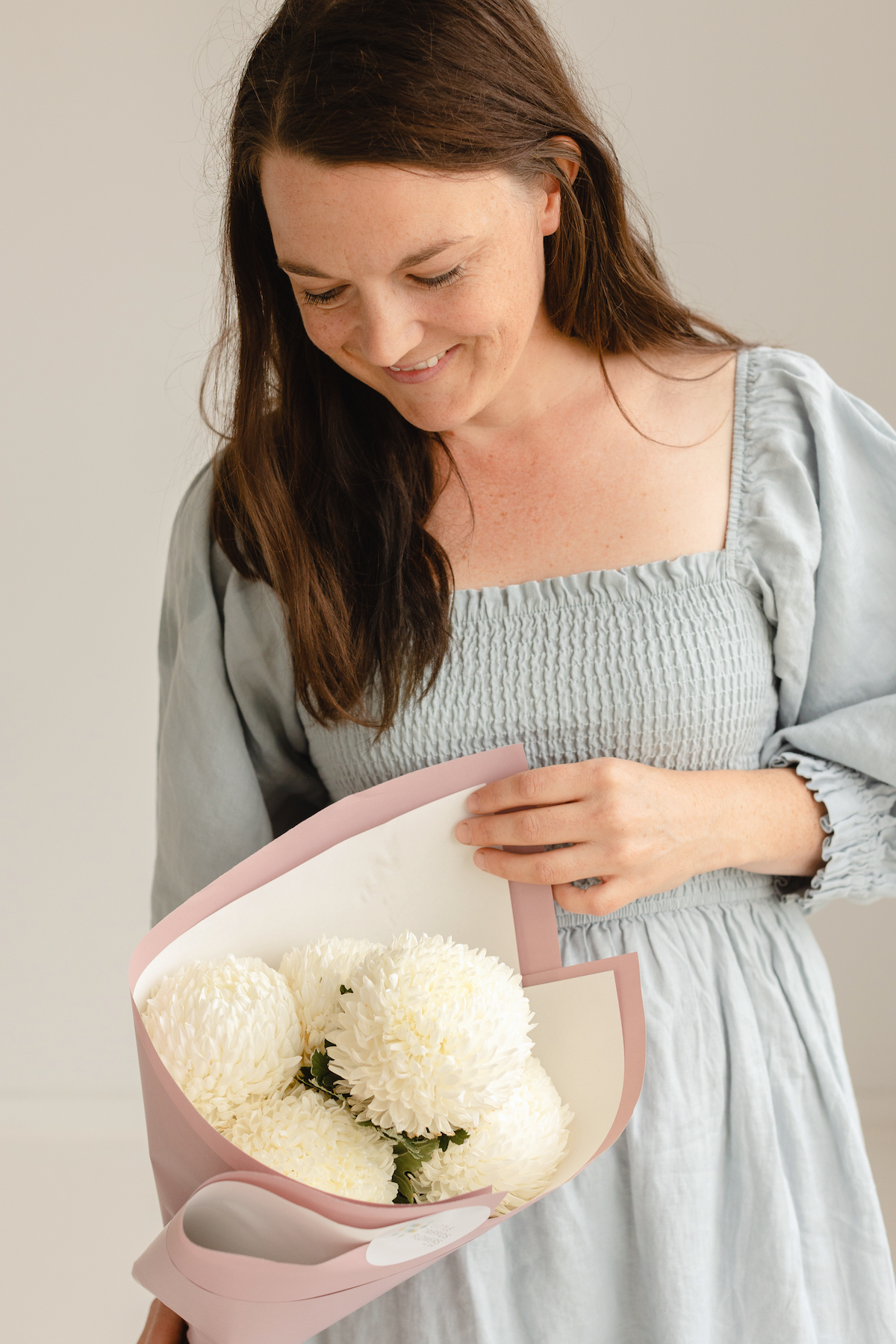 Bouquet of 5 white chrysanthemums being held by a woman for Mothering Sunday.