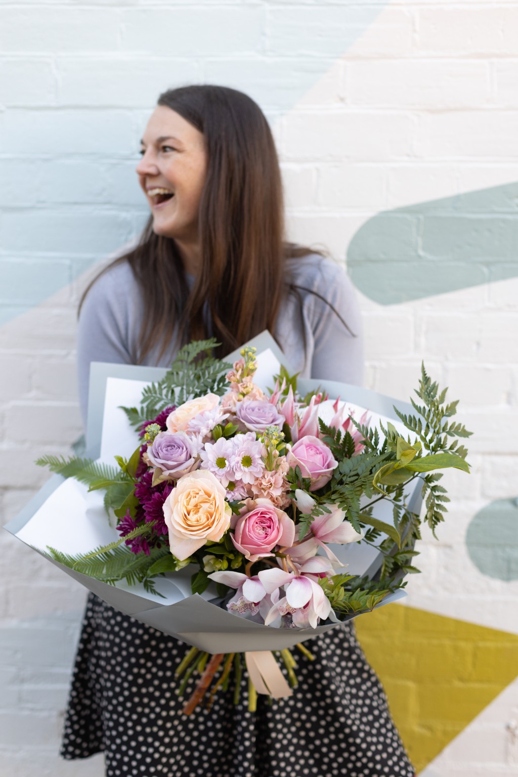 Laughing woman holding an extra large bouquet of beautiful flowers.